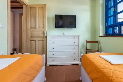 a bedroom with two beds and a dresser with a tv at Chalki Jewel in Halki