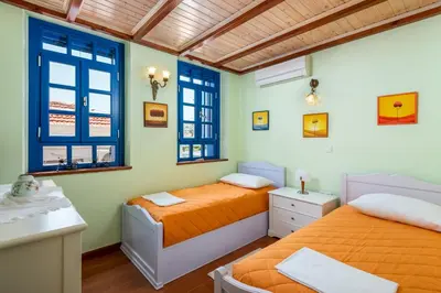 two beds in a room with two windows at Chalki Jewel in Halki