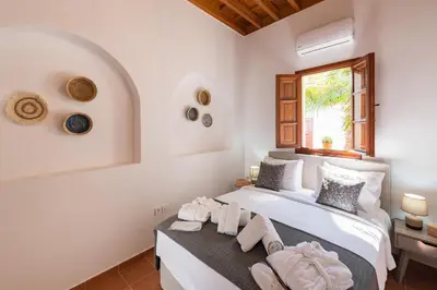a white bedroom with a bed and a window at Althea Villa in Líndos