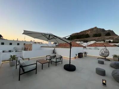 a patio with chairs and a table and an umbrella at Althea Villa in Líndos