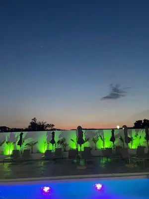 a pool with chairs and a wall with green lights at FRESH HOTEL FALIRAKI in Faliraki