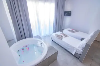 a bathroom with a tub and two beds in it at FRESH HOTEL FALIRAKI in Faliraki