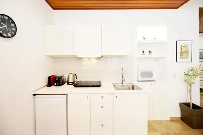 a kitchen with white cabinets and a sink and a clock at Martha's Home in Rhodes Town
