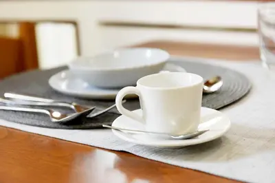 a white coffee cup and saucers on a table at Martha's Home in Rhodes Town