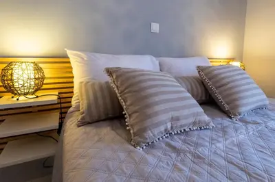 a bed with two pillows and a lamp on a table at Island Rodos Pool Suites in Ialyssos