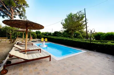 a swimming pool with two lounge chairs and an umbrella at Island Rodos Pool Suites in Ialyssos