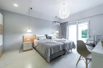 a white bedroom with a bed and a chair at Island Rodos Pool Suites in Ialyssos