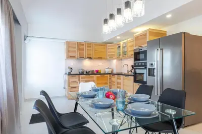 a kitchen with a glass table with chairs and a refrigerator at Island Rodos Pool Suites in Ialyssos