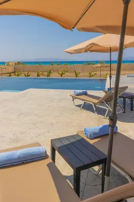 a table and chairs with an umbrella on the beach at Viva Tourismo Resort (naturist club) in Paradeísion