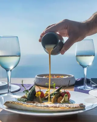a person pouring wine into a plate of food at Viva Tourismo Resort (naturist club) in Paradeísion