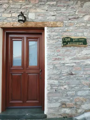 a wooden door on a stone building with a sign at STONE GUESTHOUSE in Áyios Isídhoros