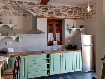 a kitchen with green cabinets and a refrigerator at STONE GUESTHOUSE in Áyios Isídhoros