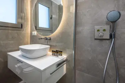 a bathroom with a sink and a shower with a mirror at Panorama Luxury Penthouse in Ixia