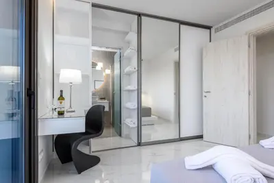 a white bedroom with a black chair and a glass wall at Panorama Luxury Penthouse in Ixia