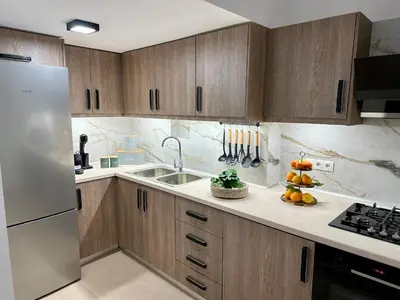 a kitchen with wooden cabinets and a stainless steel refrigerator at Anemos Villa Stegna in Archangelos