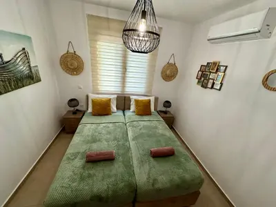 a large green bed in a room with a window at Anemos Villa Stegna in Archangelos