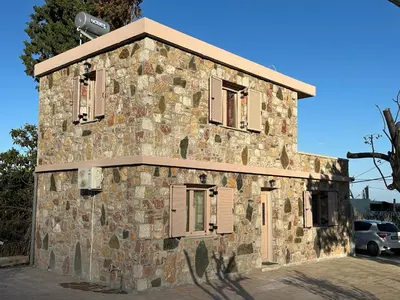 an old stone building with shutters on it at Anemos Villa Stegna in Archangelos
