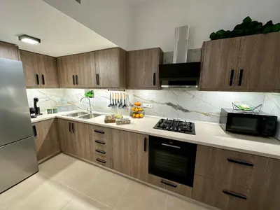 a kitchen with wooden cabinets and a stainless steel refrigerator at Anemos Villa Stegna in Archangelos