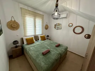 a bedroom with a green bed with a window at Anemos Villa Stegna in Archangelos