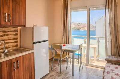 a kitchen with a refrigerator and a table with a window at Despinas Seafront Apartments,Haraki in Haraki