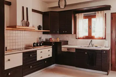 a kitchen with black and white cabinets and a sink at Maya pool & mountain view villa in Koskinou
