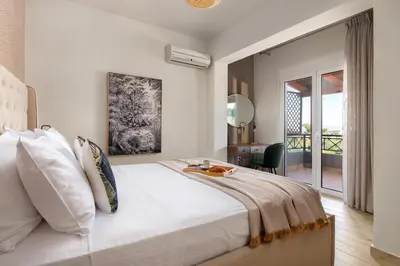 a bedroom with a large white bed and a desk at Emmelia Villa in Ialyssos