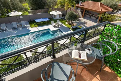 a balcony with a table and chairs and a swimming pool at Emmelia Villa in Ialyssos