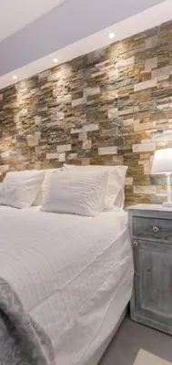 a bedroom with a white bed and a stone wall at Rhodes Center Luxurious Penthouse in Rhodes Town