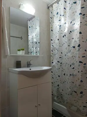 a bathroom with a sink and a shower with a mirror at Comfy Cozy Iksia in Ixia