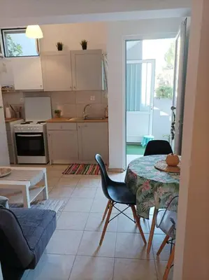 a living room with a table and chairs and a kitchen at Comfy Cozy Iksia in Ixia