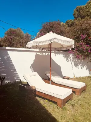 two beds under an umbrella in the grass at Naya pool & garden view bungalow in Koskinou