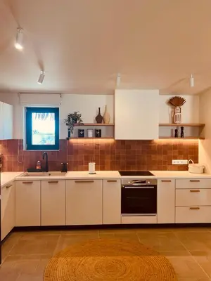 a kitchen with white cabinets and a black oven at Naya pool & garden view bungalow in Koskinou