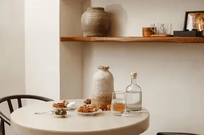 a white table with a bottle and a glass at Noema Lindos - Angeliki Suite in Líndos