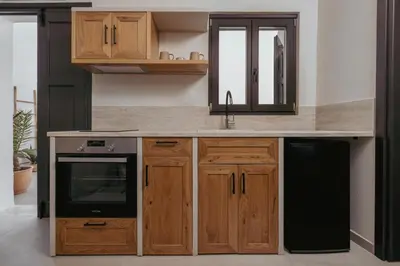 a kitchen with wooden cabinets and a black dishwasher at Noema Lindos - Angeliki Suite in Líndos