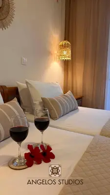 a bed with two glasses of wine and flowers on it at ANGELOS STUDIOS 3-4 in Faliraki Rhodes-Upper Floor in Faliraki