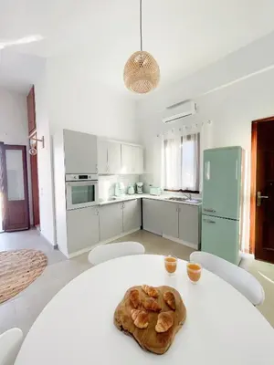 a white kitchen with a table with bread on it at Casa Chara 2 in Symi