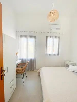 a white bedroom with a bed and a desk at Casa Chara 2 in Symi