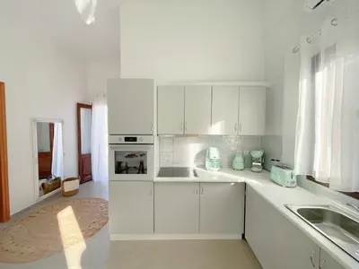 a white kitchen with white cabinets and a sink at Casa Chara 2 in Symi