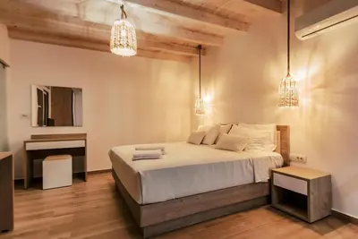 a bedroom with a bed and a desk and chandeliers at Myrovolos luxury Eneida's house in Ialyssos