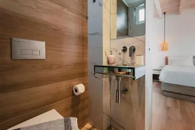 a small bathroom with a bed and a glass shelf at Myrovolos luxury Eneida's house in Ialyssos