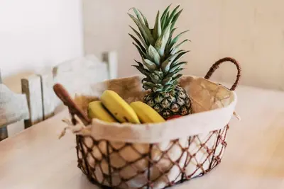 a basket with a pineapple and bananas on a table at Myrovolos luxury Eneida's house in Ialyssos