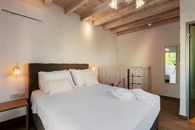 a bedroom with a large white bed with two towels on it at Myrovolos luxury Angie's house in Ialyssos