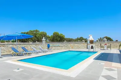 a swimming pool with two chairs and an umbrella at Pearl Villas Gennadi in Gennadi