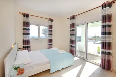 a bedroom with a bed and a large window at Pearl Villas Gennadi in Gennadi