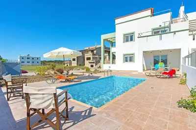 a villa with a swimming pool in front of a house at Pearl Villas Gennadi in Gennadi