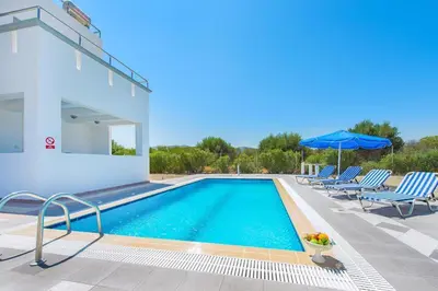 a villa with a swimming pool and two lawn chairs at Pearl Villas Gennadi in Gennadi