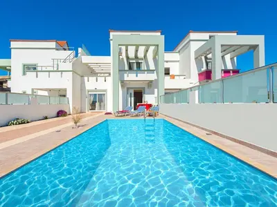 a villa with a swimming pool in front of a house at Pearl Villas Gennadi in Gennadi