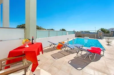 a patio with a table and chairs and a pool at Pearl Villas Gennadi in Gennadi