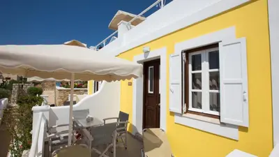 a yellow building with a table and an umbrella at Chic & Modern Apartments with swim access in Halki