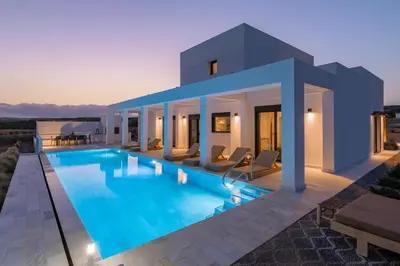 a villa with a swimming pool at dusk at Seastar Villa Large Pool & Jacuzzi Retreat in Lachania